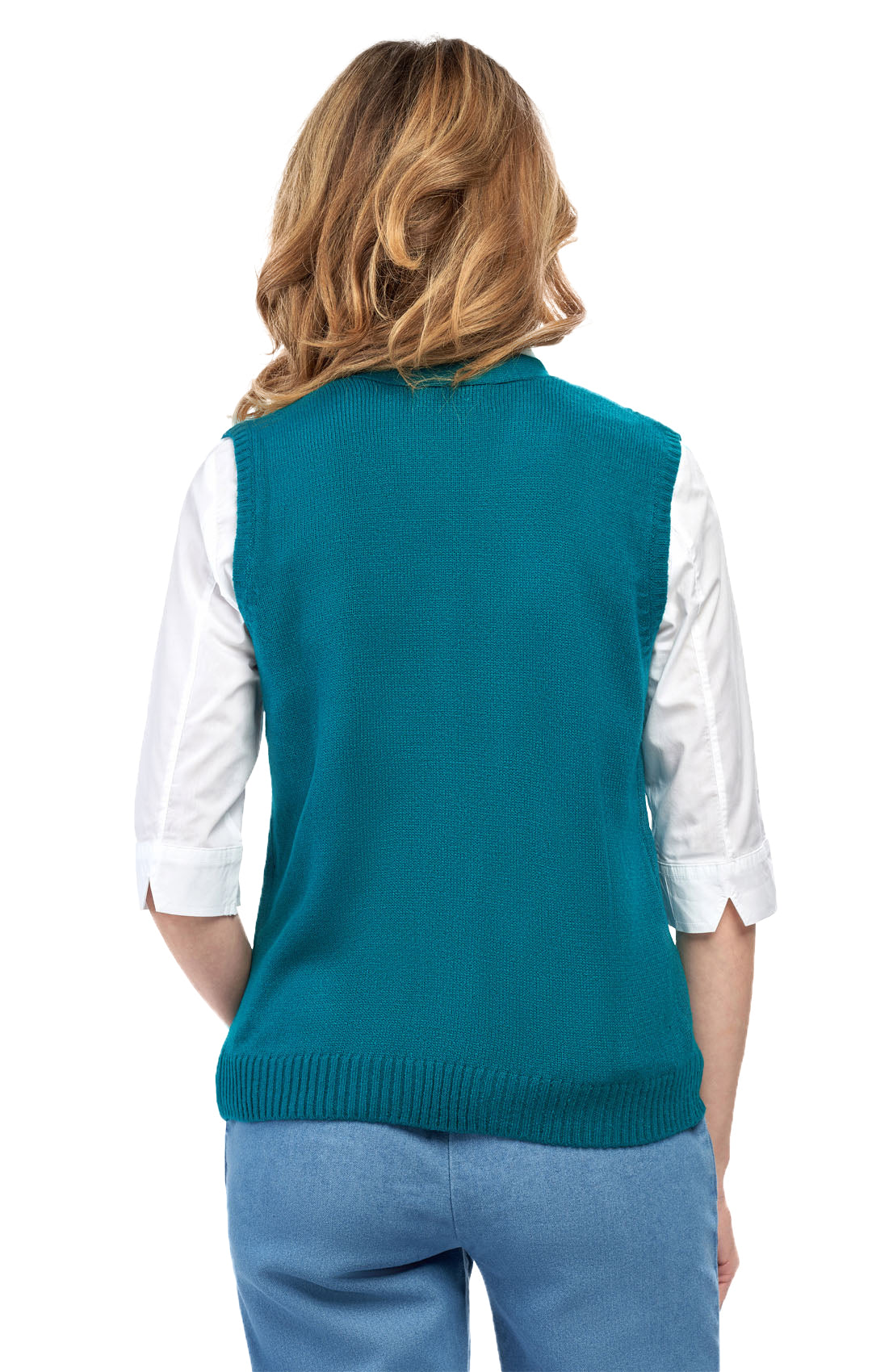 Person wearing a teal sweater vest over a white shirt with blue pants on a white background
